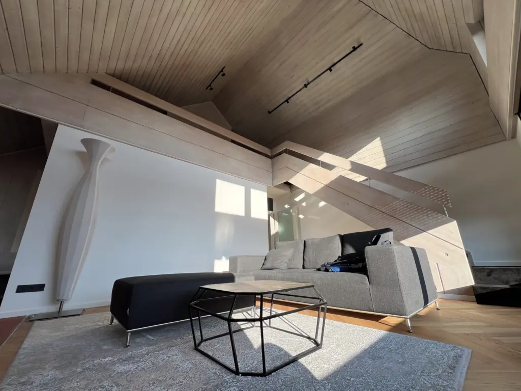 Wohnzimmer mit heller Holzdecke und Lichtschienen im Dachgeschoss