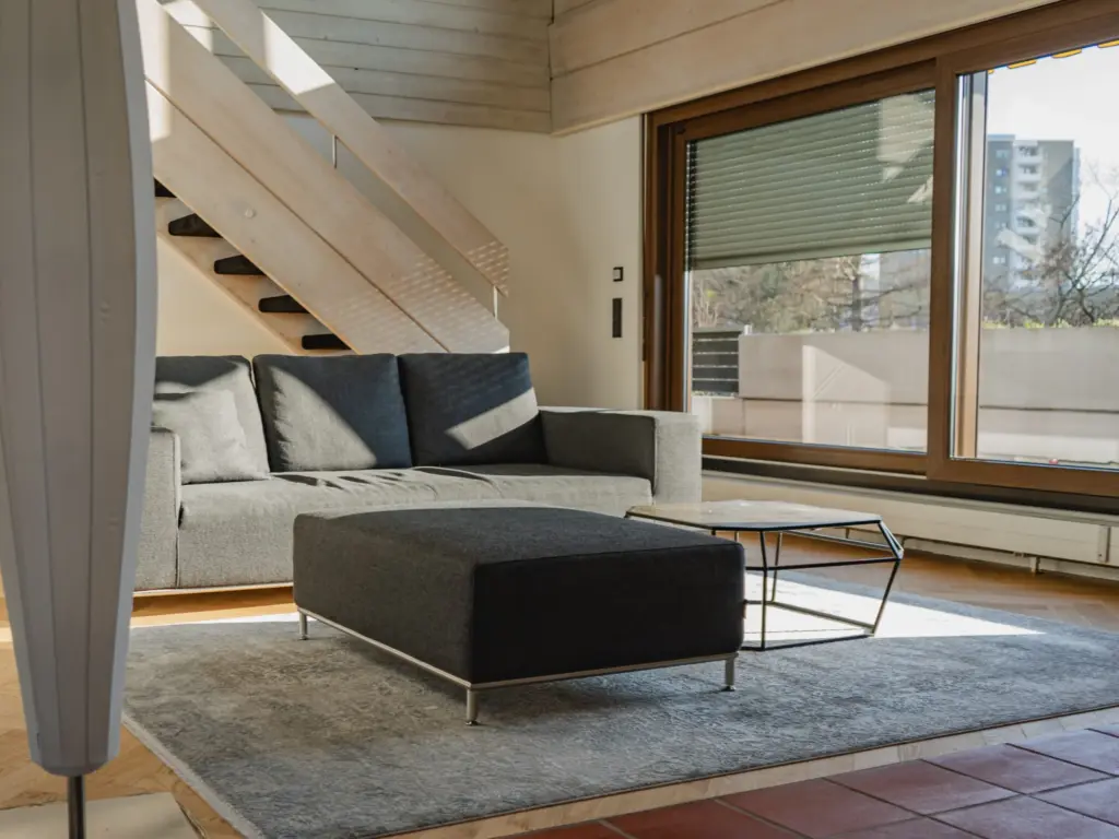 Wohnzimmer mit Treppe und großer Fensterfront im umgebauten Bestand