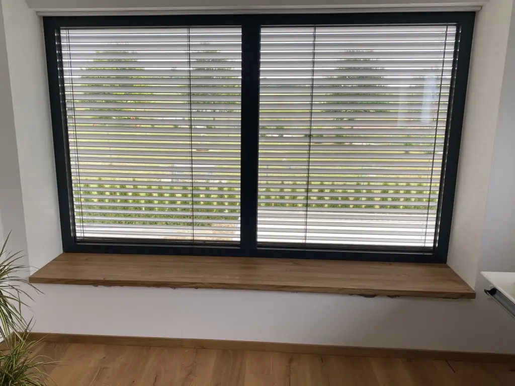 Großes anthrazitfarbenes Fenster mit Raffstore und Sitzbank aus Holz