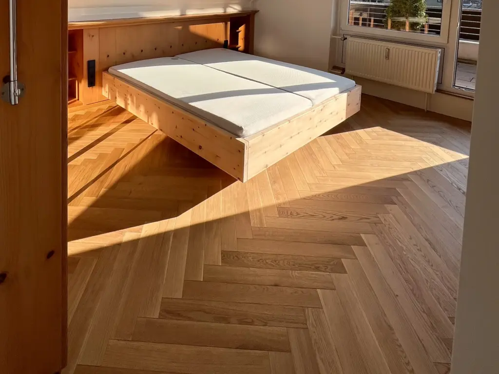 Schlafzimmer mit Fischgrätparkett aus Eiche und Holzbett