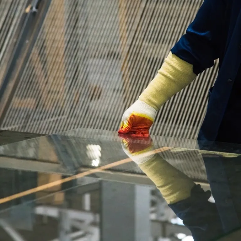 Handwerker mit Schutzhandschuh beim Prüfen einer Glasscheibe