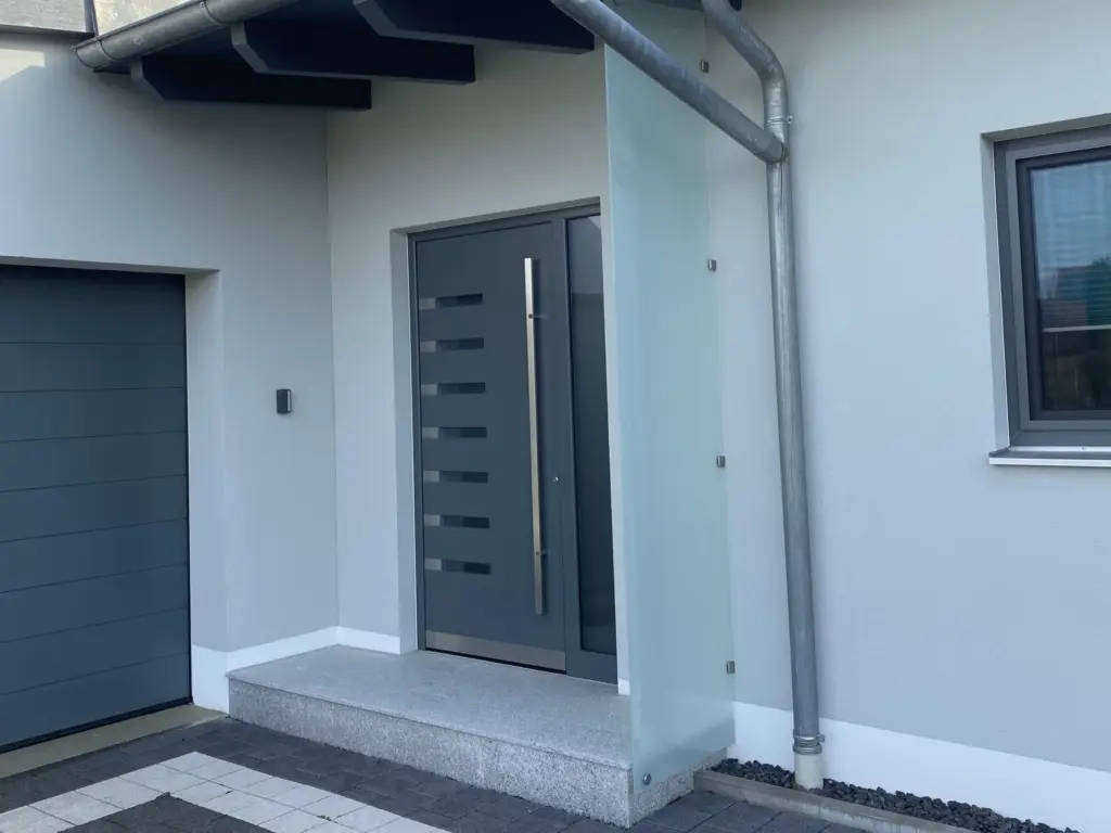 Glasvordach über einer anthrazitfarbenen Haustür