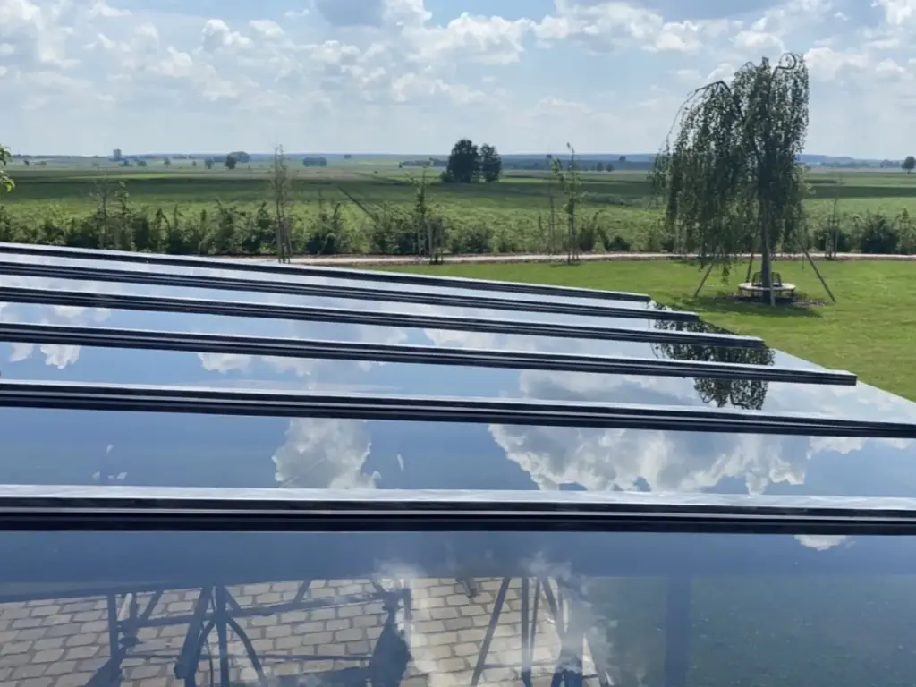 Glasdach einer Terrasse mit Spiegelung der Wolken