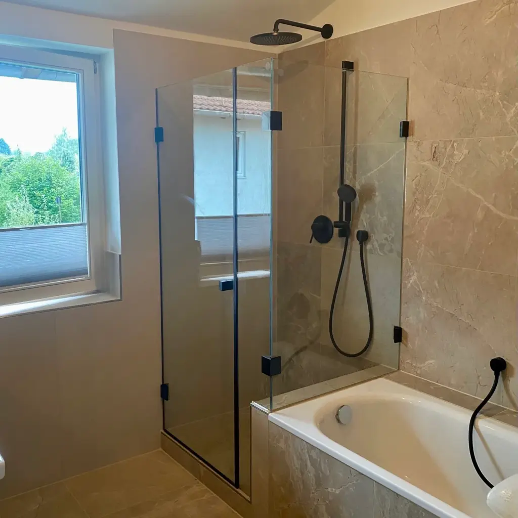 Glasdusche über der Badewanne mit schwarzen Armaturen