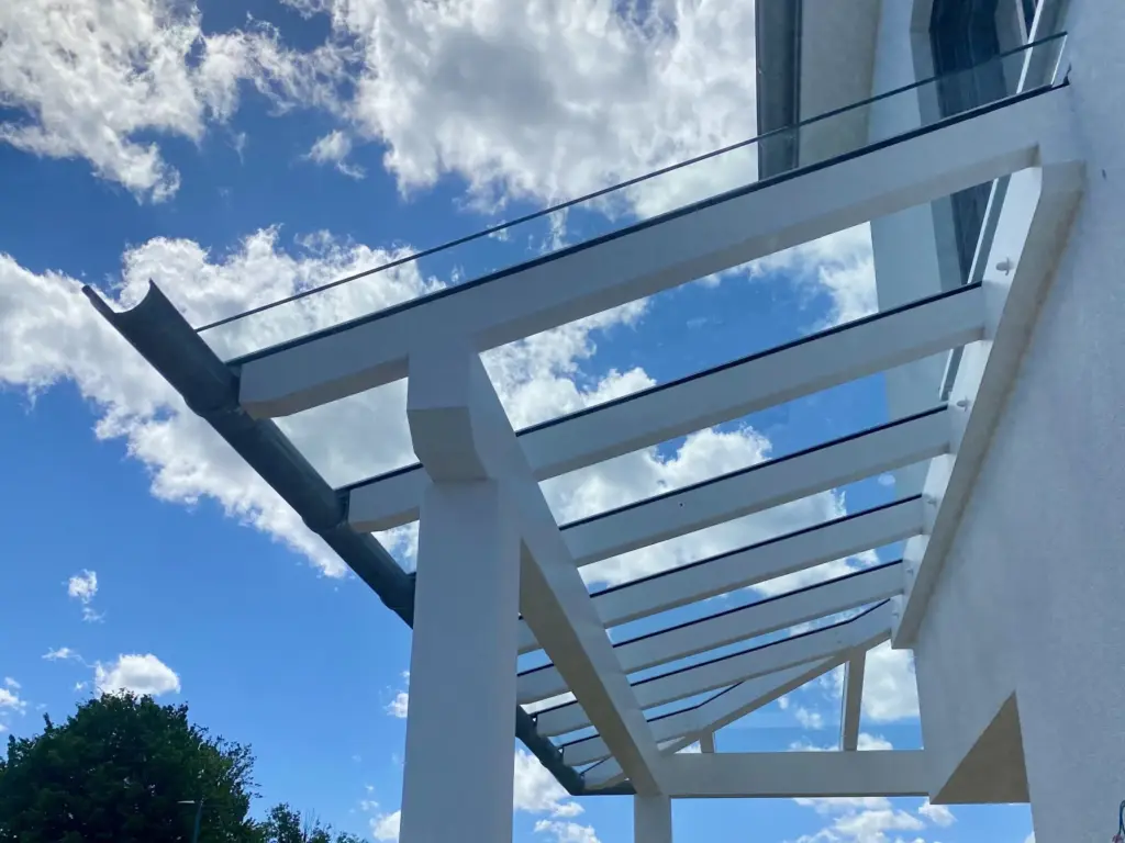 Glasüberdachung mit weißer Unterkonstruktion vor blauem Himmel