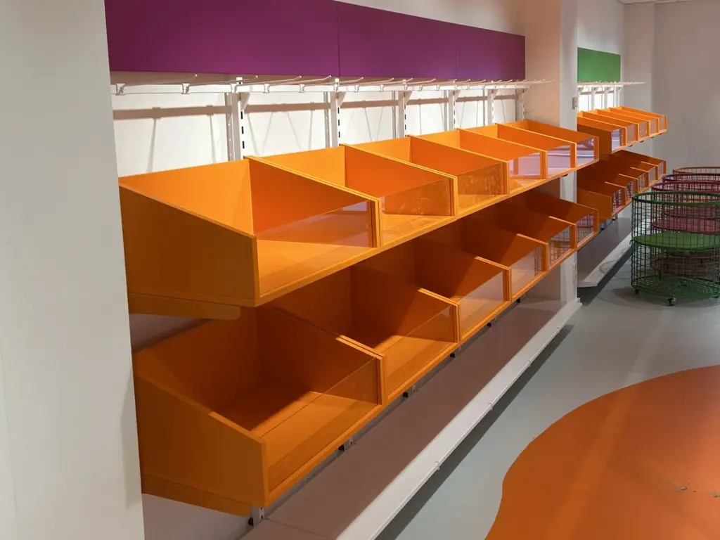 Wandregal mit orangen Fächern im Ladenbau